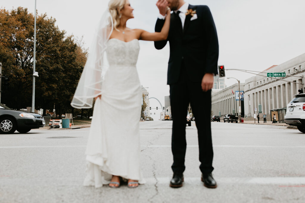 A bride and groom stand in the crosswalk and kiss outside of the St. Louis Union Hotel.