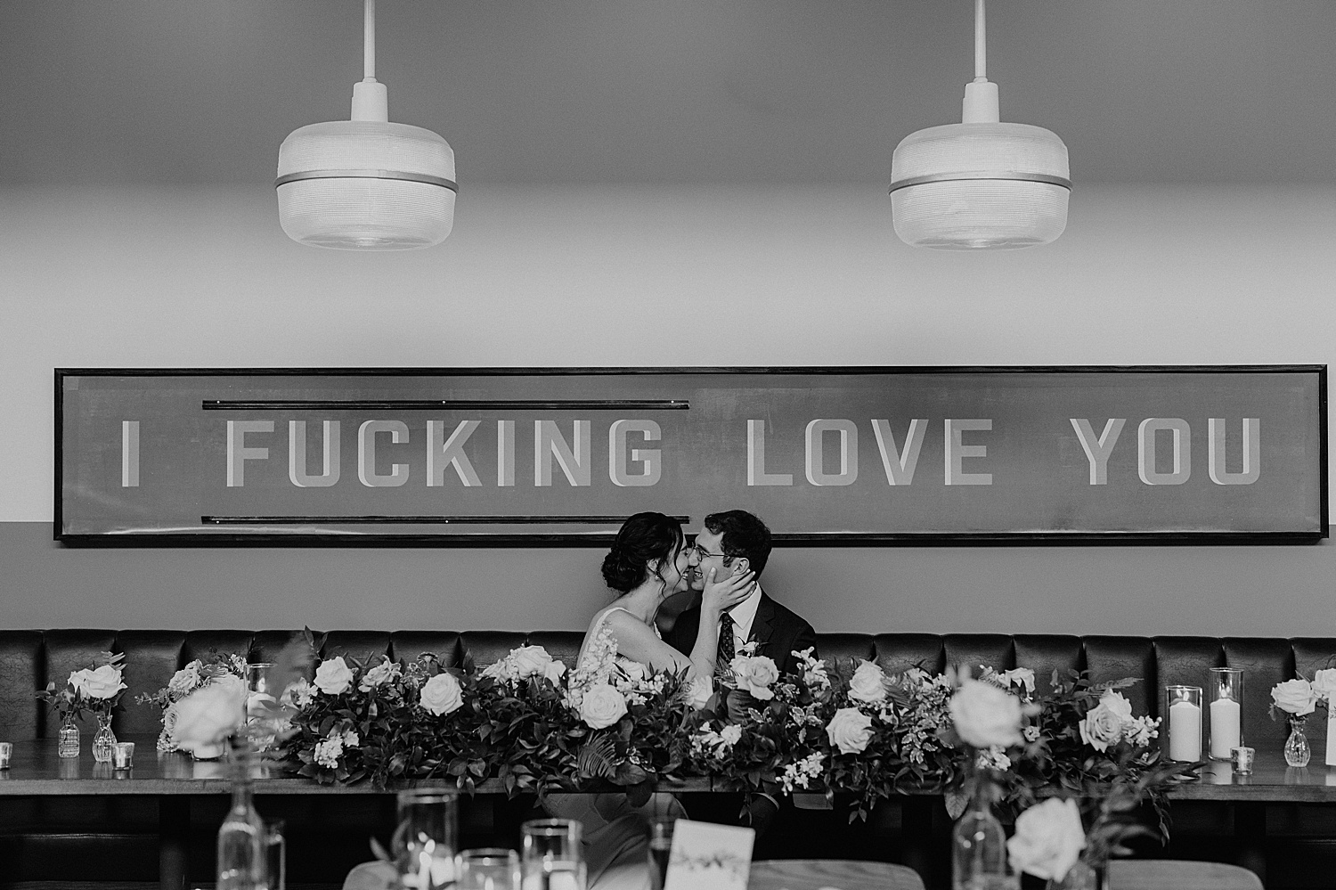 Couple under sign that says "I fucking love you"
