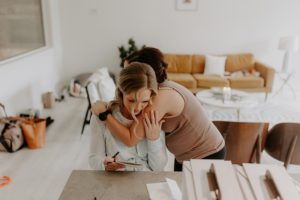 Bride crying writing her husband a note being comforted by sister