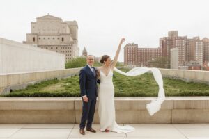 Bride throws veil next to groom who is smiling at the Pulitzer Arts Foundation.