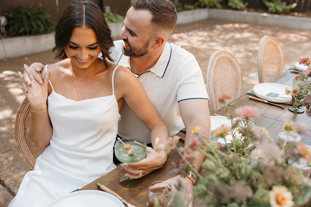 A bride and groom sit together at a dining table with florals at the a.casa wedding venue in St. Louis, Missouri