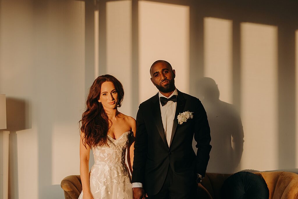 A bride and groom looking at the camera, with sun illuminating their face at The Dogwood in the Grove in St. Louis, Missouri.