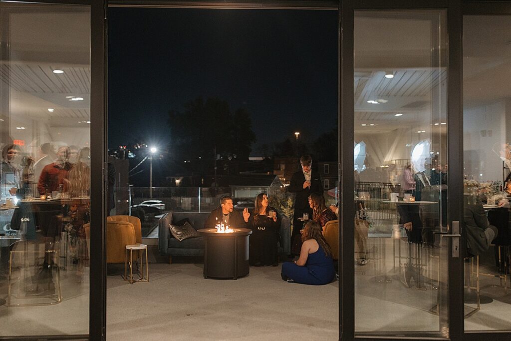 A group of adult friends talking and laughing on a balcony.