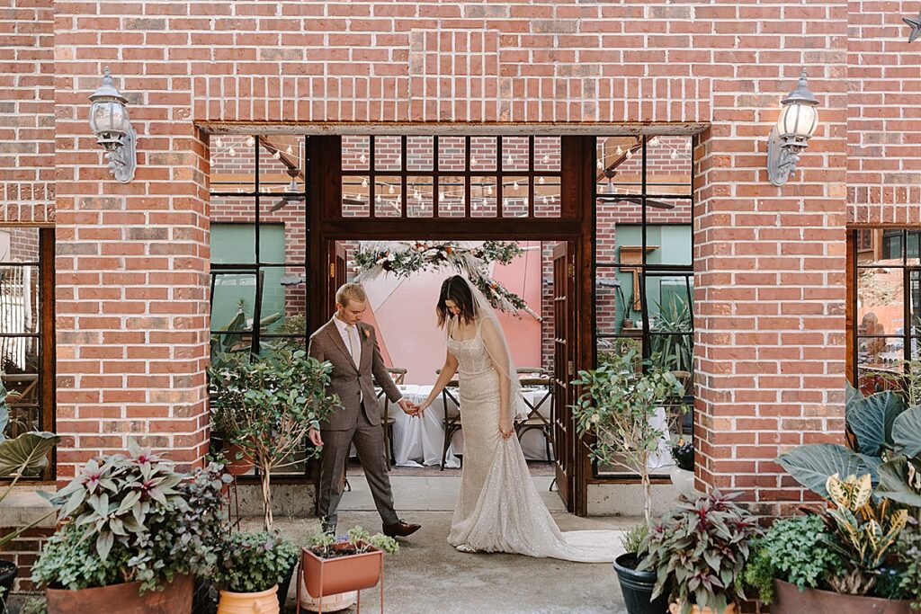 A bride and groom holding hands outside of Verde on Cherokee in St. Louis, Missouri.