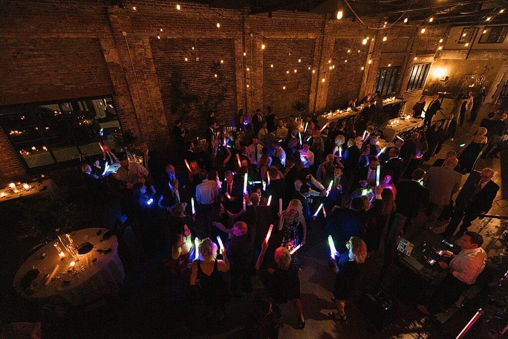 An aerial view of guests dancing at night, while holding glow sticks, at Wild Carrot wedding venue.