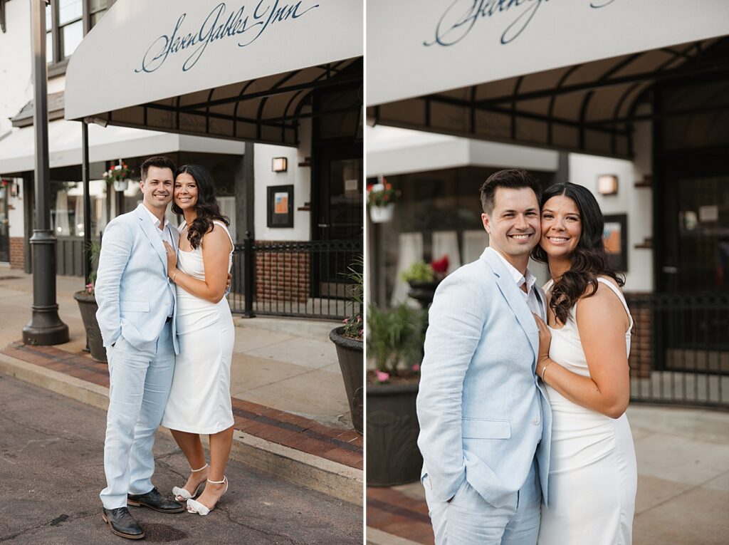 Man in light blue suit with woman in white dress smile at the camera in front of Seven Gables Inn in Clayton, MIssouri.