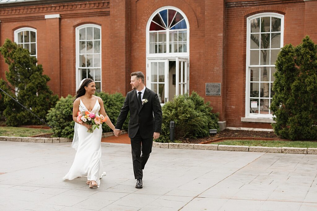 Bride and groom walking in front of the Piper Palm House after their Tower Grove Park wedding in St. Louis, Missouri.