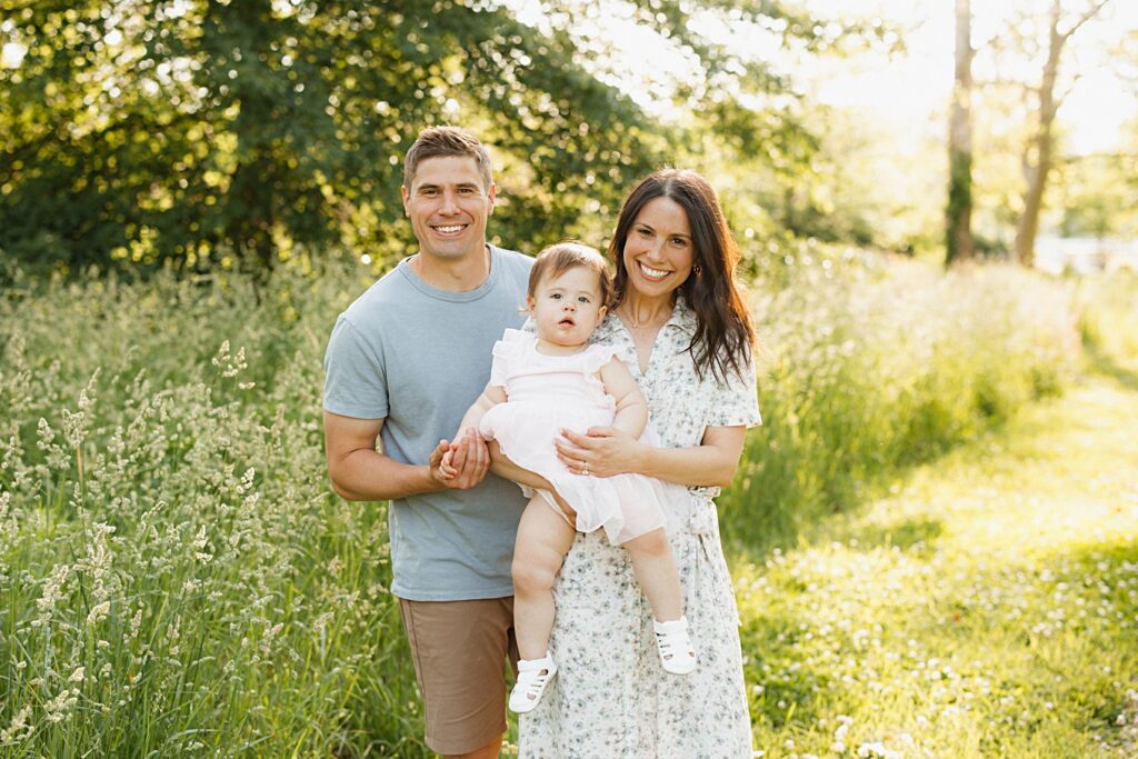 Mom wearing a floral wrap dress next to a dad wearing a blue tshirt for spring family photos.