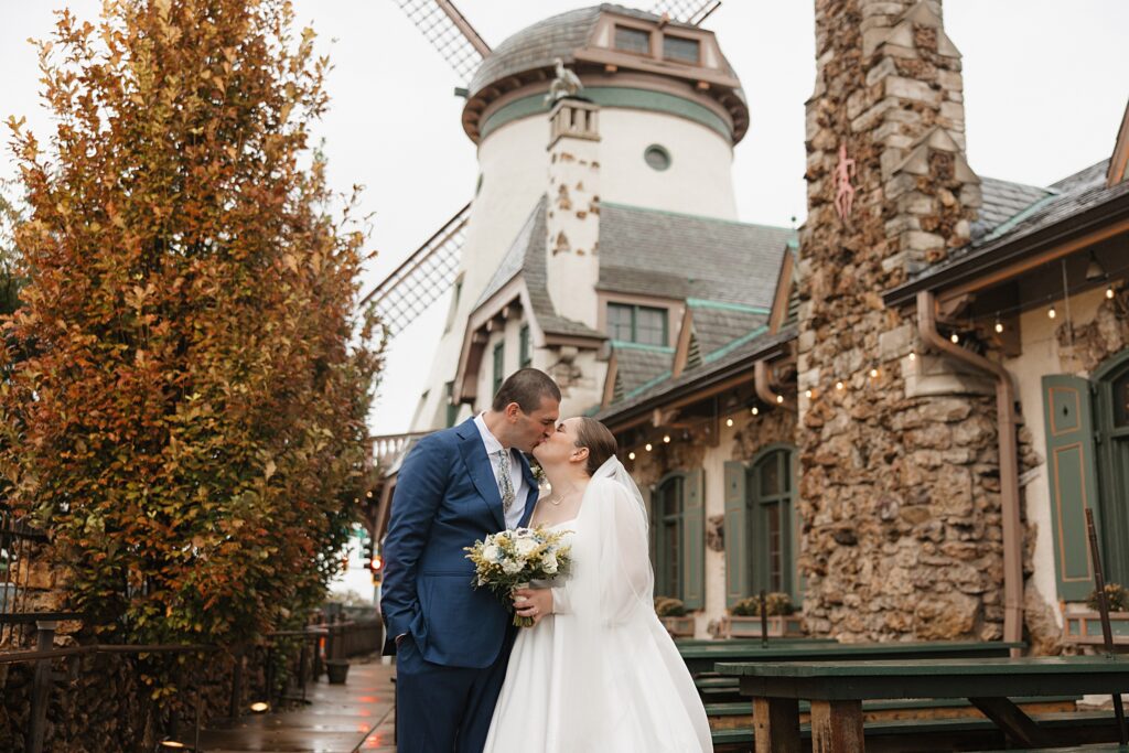 Bride and groom kiss in front of windmill at Das Bevo wedding venue in St. Louis, Missouri