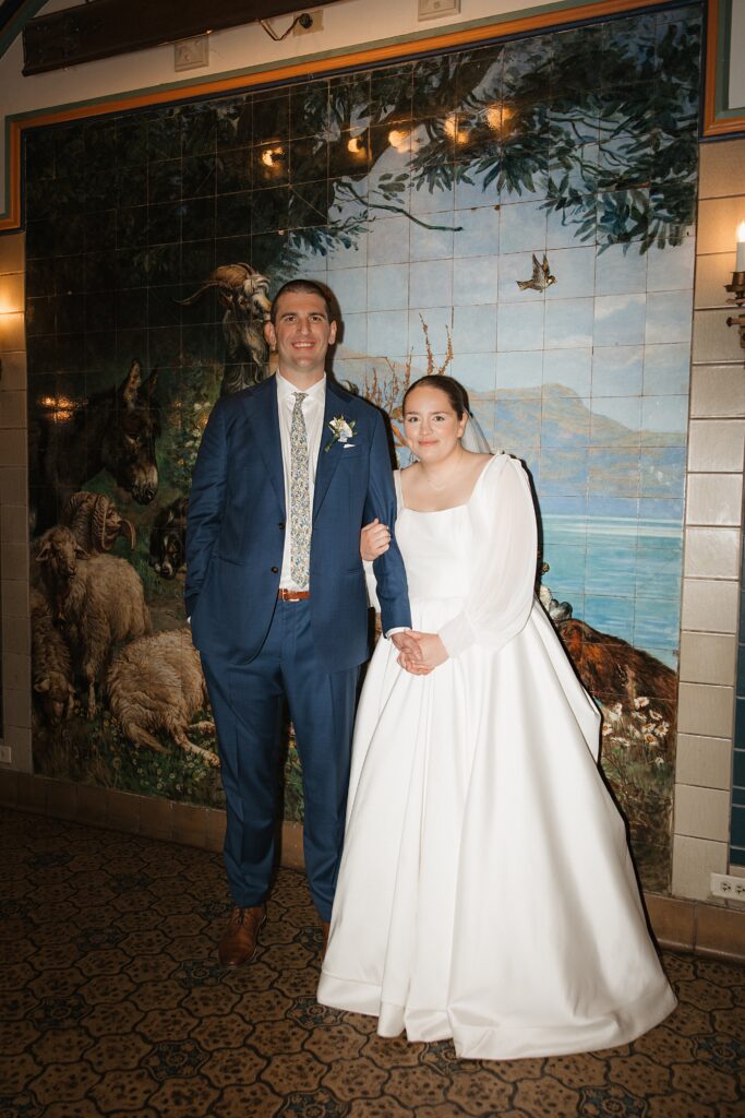Bride and groom pose in front of painted mural inside their Das Bevo wedding venue in St. Louis, Missouri