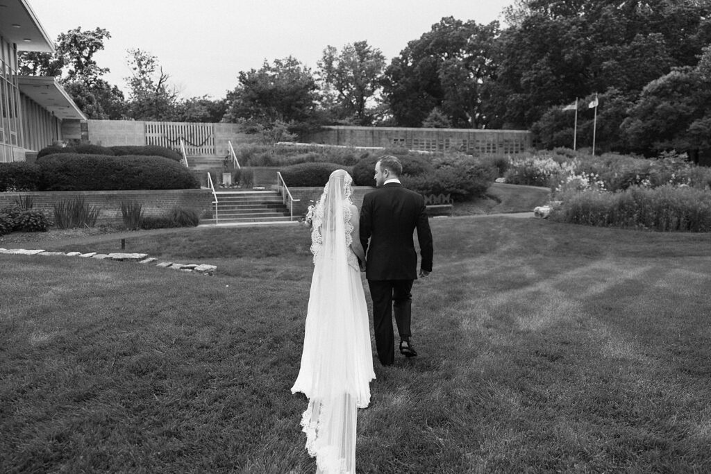 Black and white image of bride and groom walking away from ceremony at Weddings on Magnolia in St. Louis, Missouri
