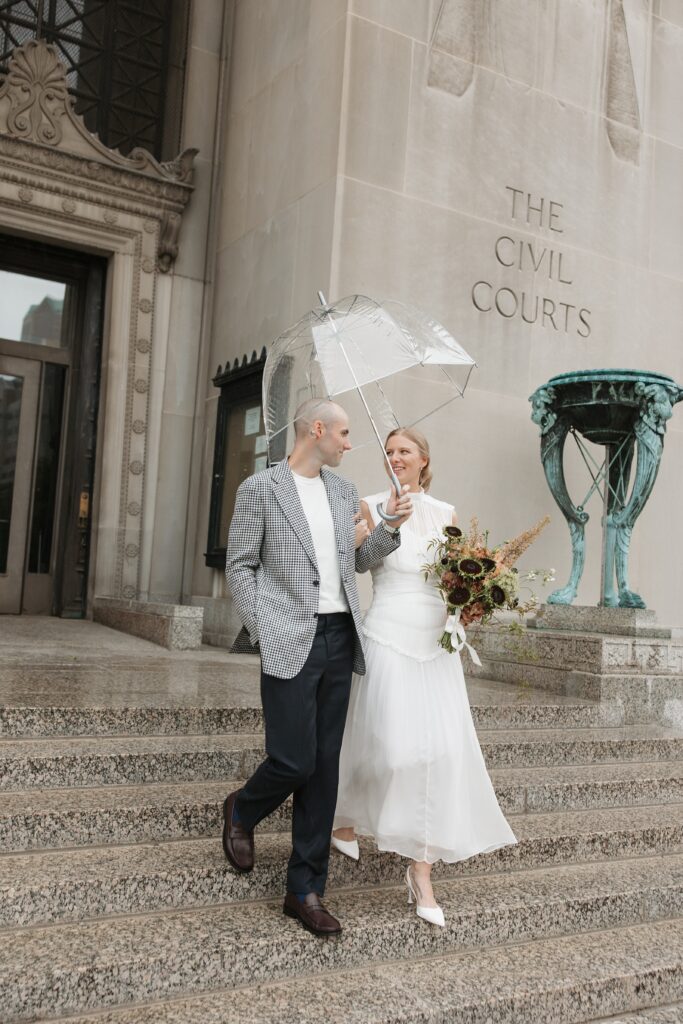 Olivia and Zach walking in the rain during their St. Louis courthouse wedding